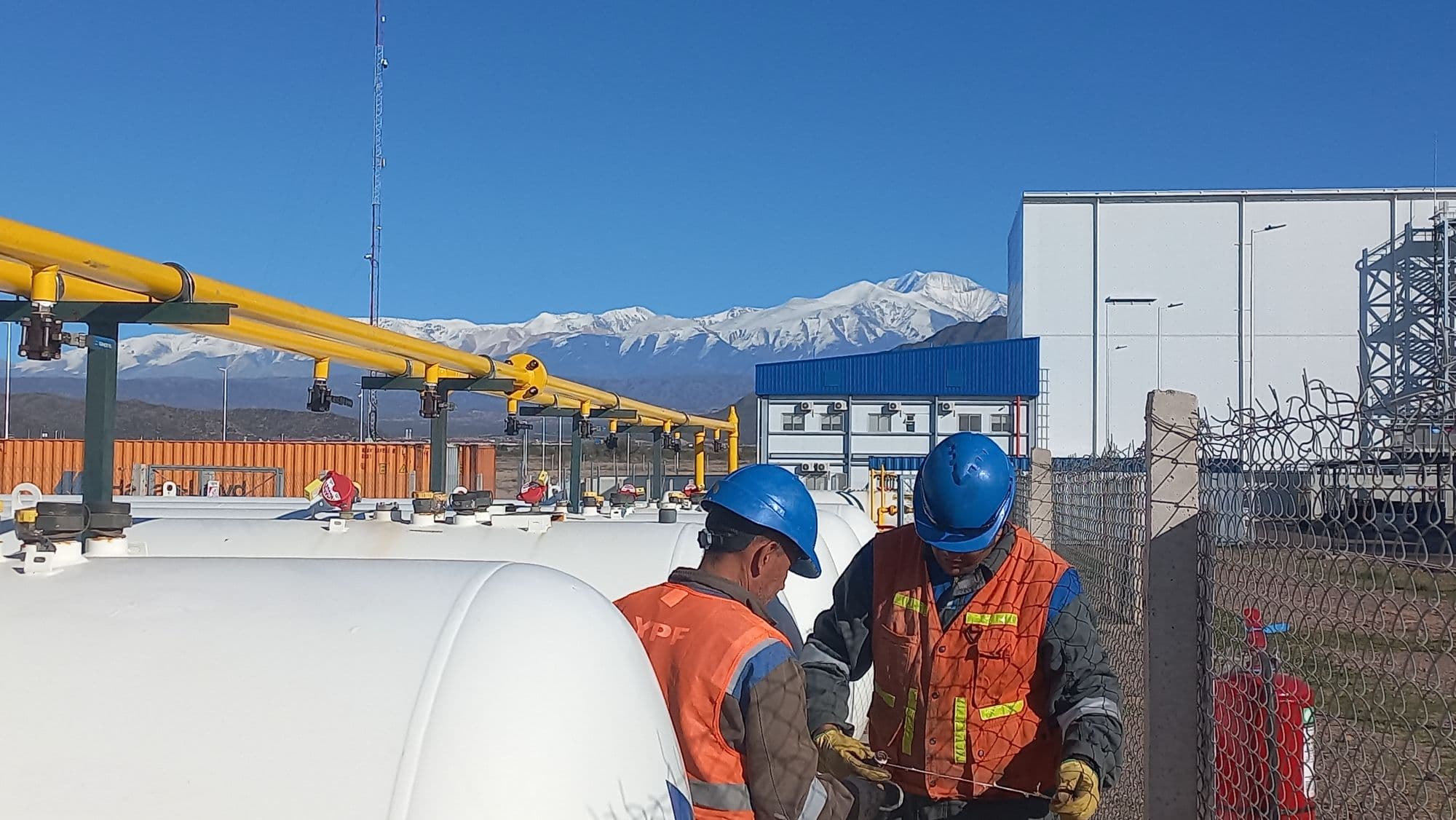 Personal de SIELC con EPP trabajando en una planta de gas con la cordillera de fondo